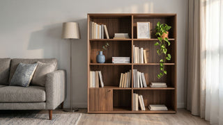 Wooden bookcase with books, plants and decor beside a grey sofa in a small Singapore living room.