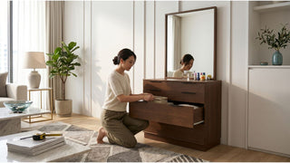 Woman opening drawer of a wooden dressing table with mirror in a compact Singapore bedroom