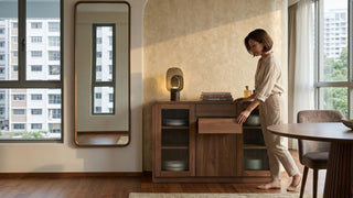 Woman organising a wooden sideboard with drawers beside a tall mirror in a compact Singapore dining space