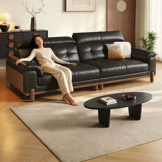 Black leather sofa on a wooden base in a living room